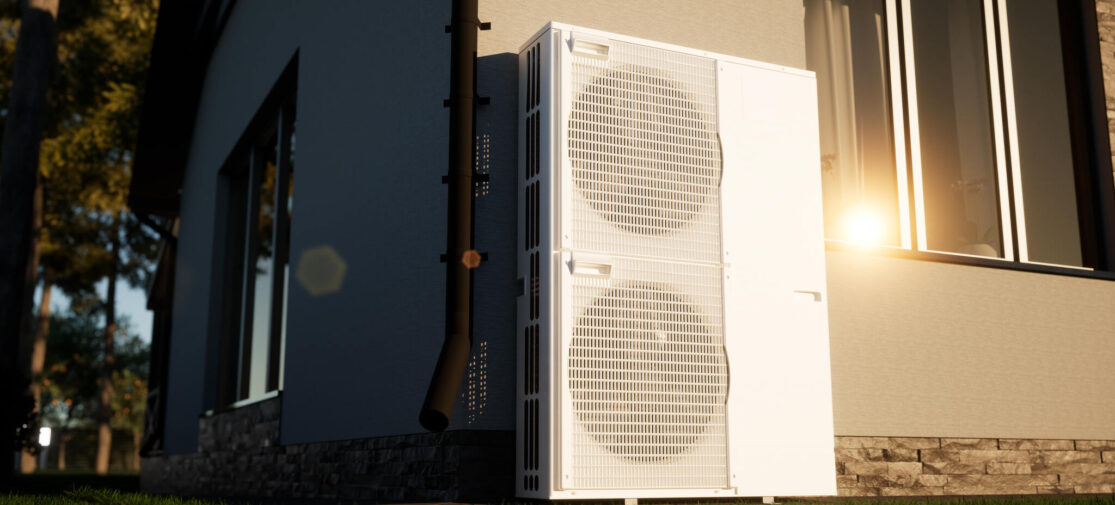 Nowoczesna pompa ciepła typu powietrze-woda zainstalowana przy ścianie energooszczędnego domu jednorodzinnego.