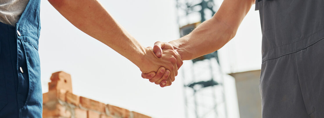 Doing handshake. Two construction workers is together at the building